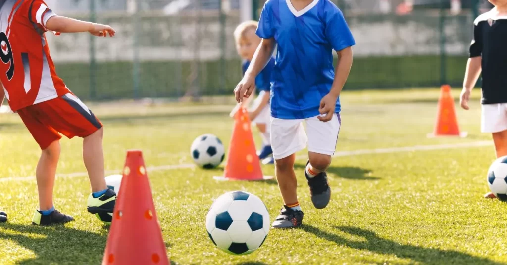 Kids practicing soccer drills with cones during a mobile personal training session focused on youth fitness