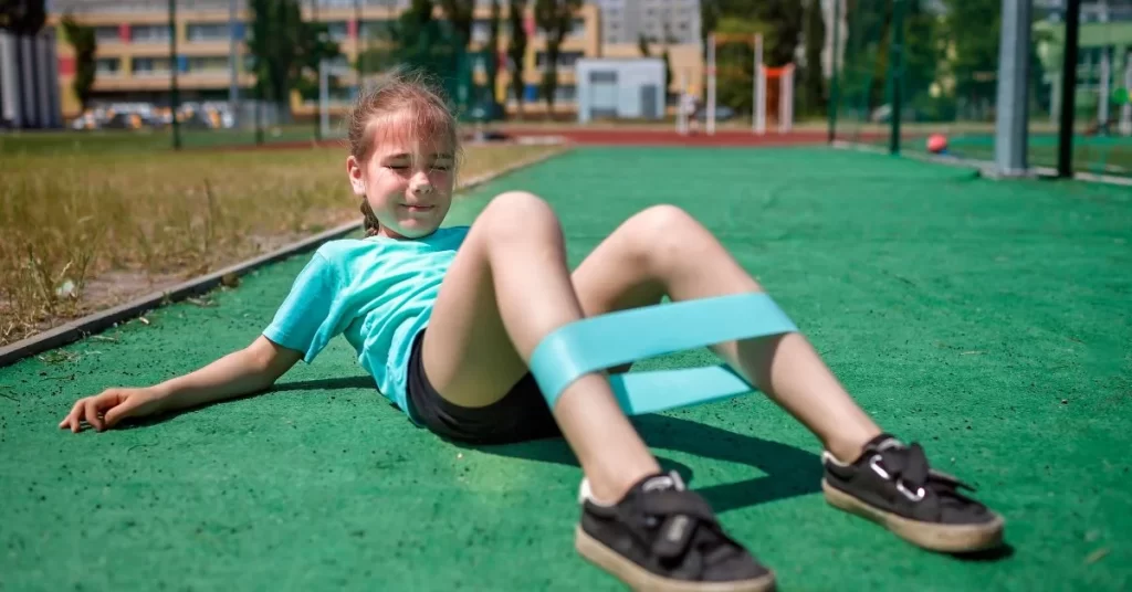 Child using a resistance band during a youth personal training exercise on an outdoor field