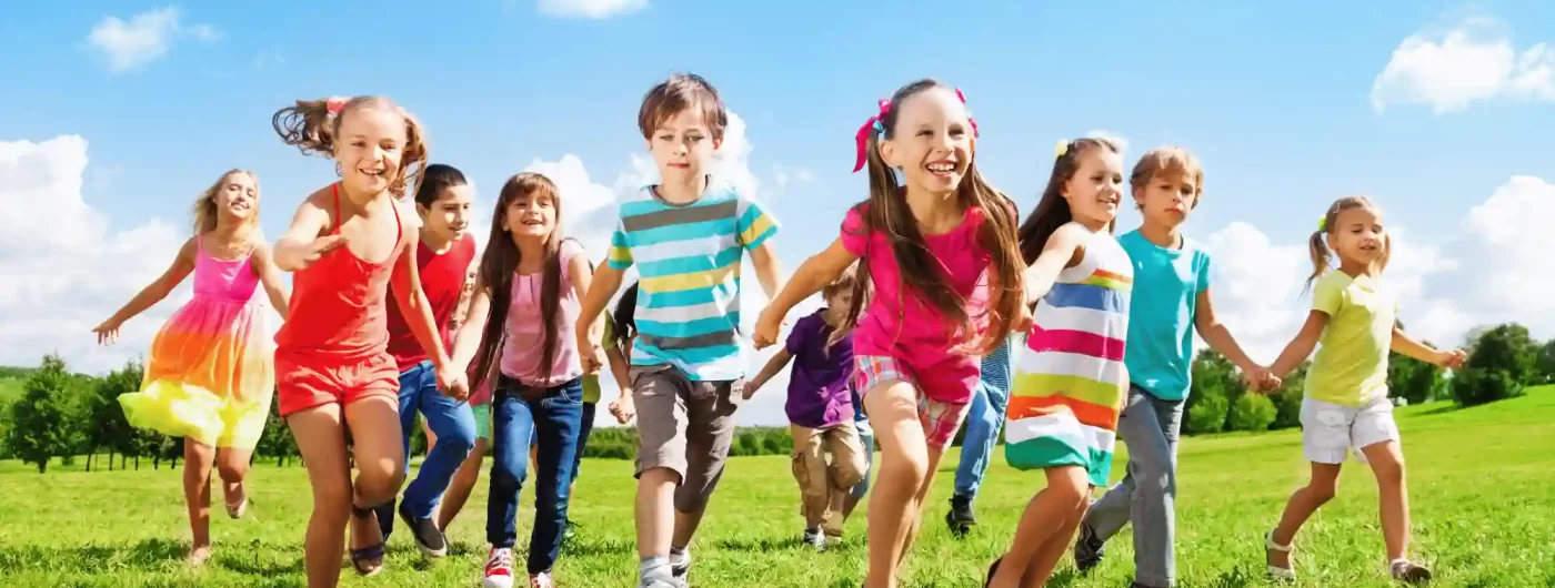 Group of children running and playing together outdoors on grass, promoting active lifestyles and kids fitness