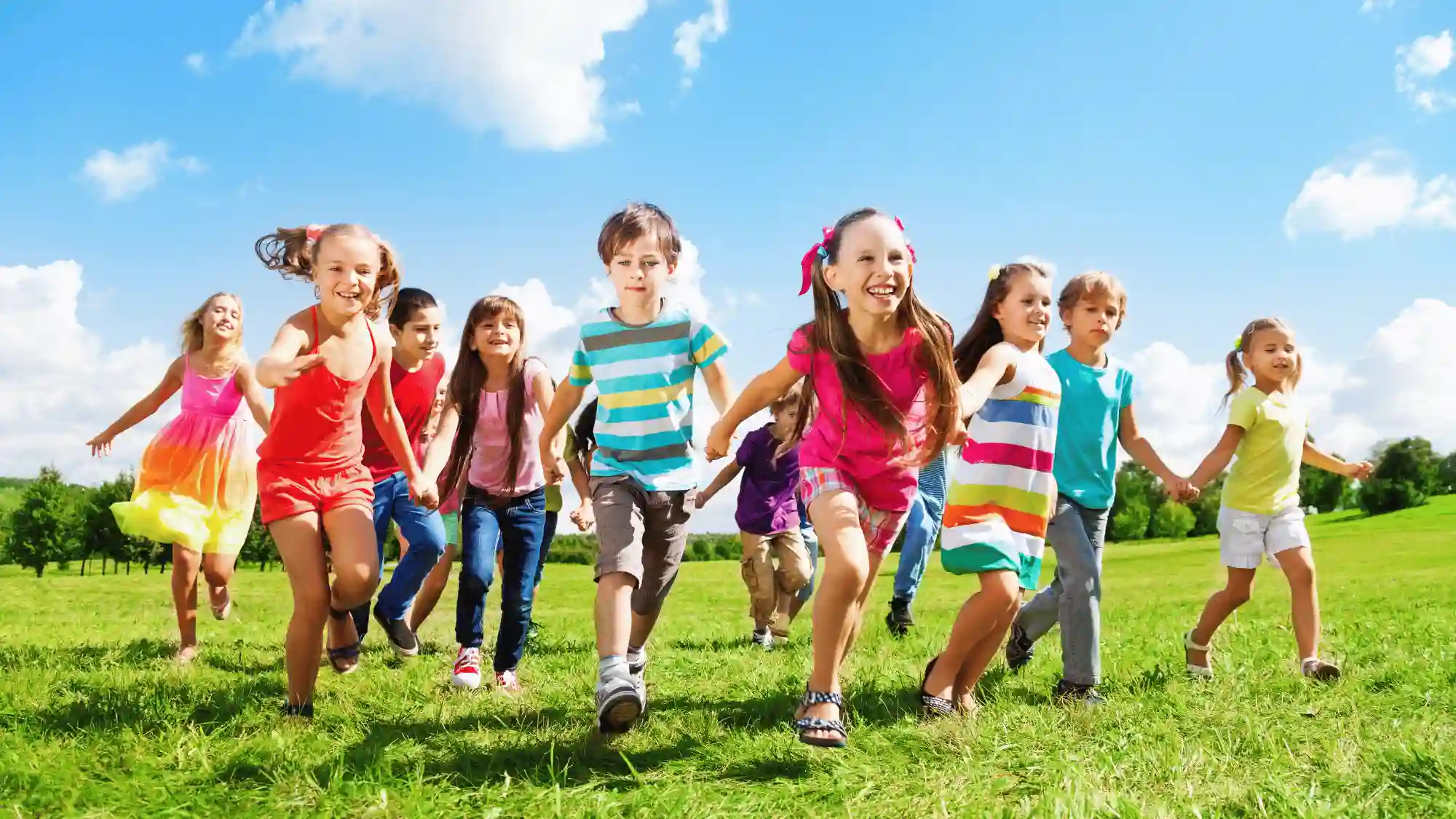 Group of children running and playing together outdoors on grass, promoting active lifestyles and kids fitness