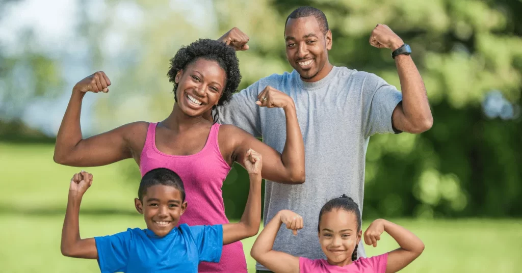 Family posing proudly and flexing muscles together after a fitness activity outdoors