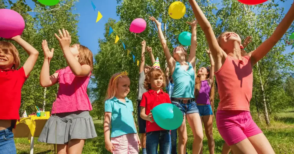 Children playing with colorful balloons outdoors during a fun and active kids birthday party.