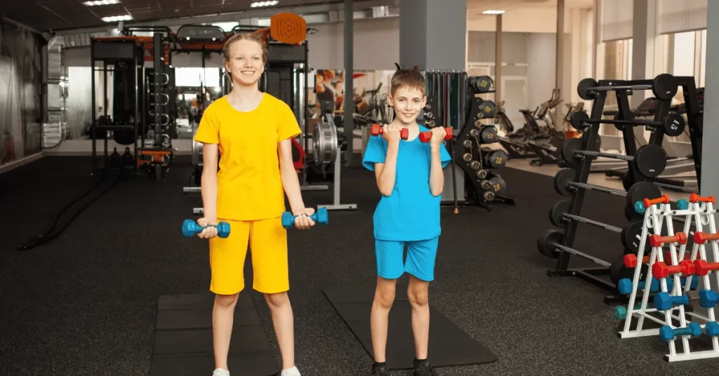 Two children exercising with dumbbells during a youth strength and fitness training session.