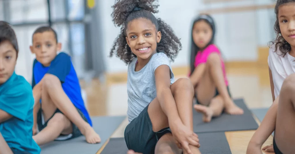 Children stretching together during a fitness session to support recovery, flexibility, and healthy exercise habits.